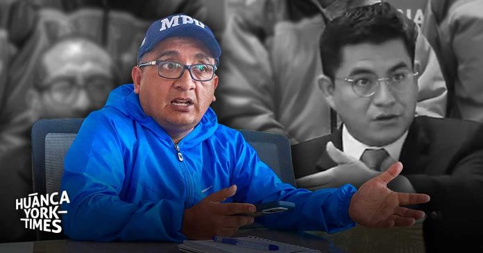 Man in a bright blue jacket and cap speaks, gesturing with hands at a table; grayscale background and a watermark reading 'HUANCA YORK TIMES'
