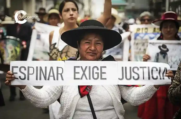 Protester in a wide-brim hat holds a banner reading 'Espinar Exige Justicia' at a street demonstration.